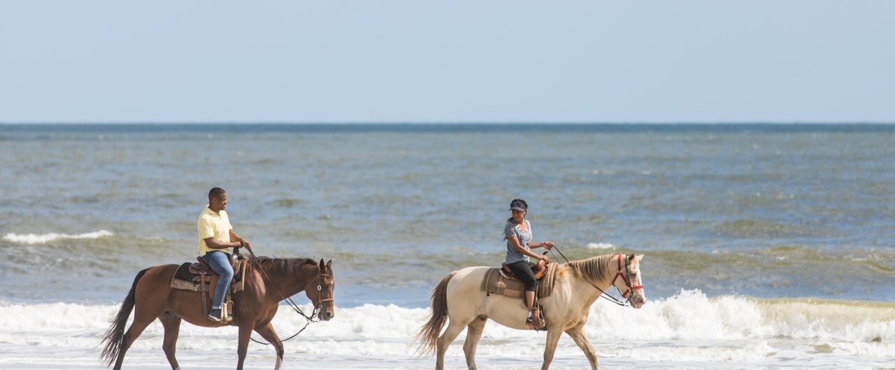 couple riding horses on beach