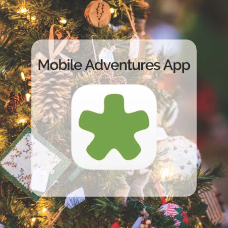 A green asterisk-shaped logo and the text Mobile Adventures App appear over a blurred, decorated Christmas tree with ornaments, pinecones, lights, and holiday cards.