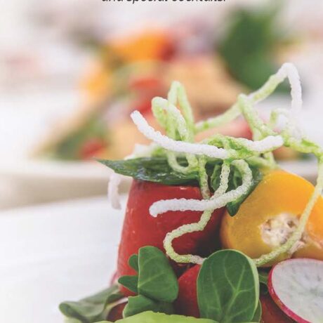 A close-up of a colorful gourmet salad featuring leafy greens, yellow cherry tomatoes, radish slices, and crispy noodle garnishes, with more blurred salads in the background.