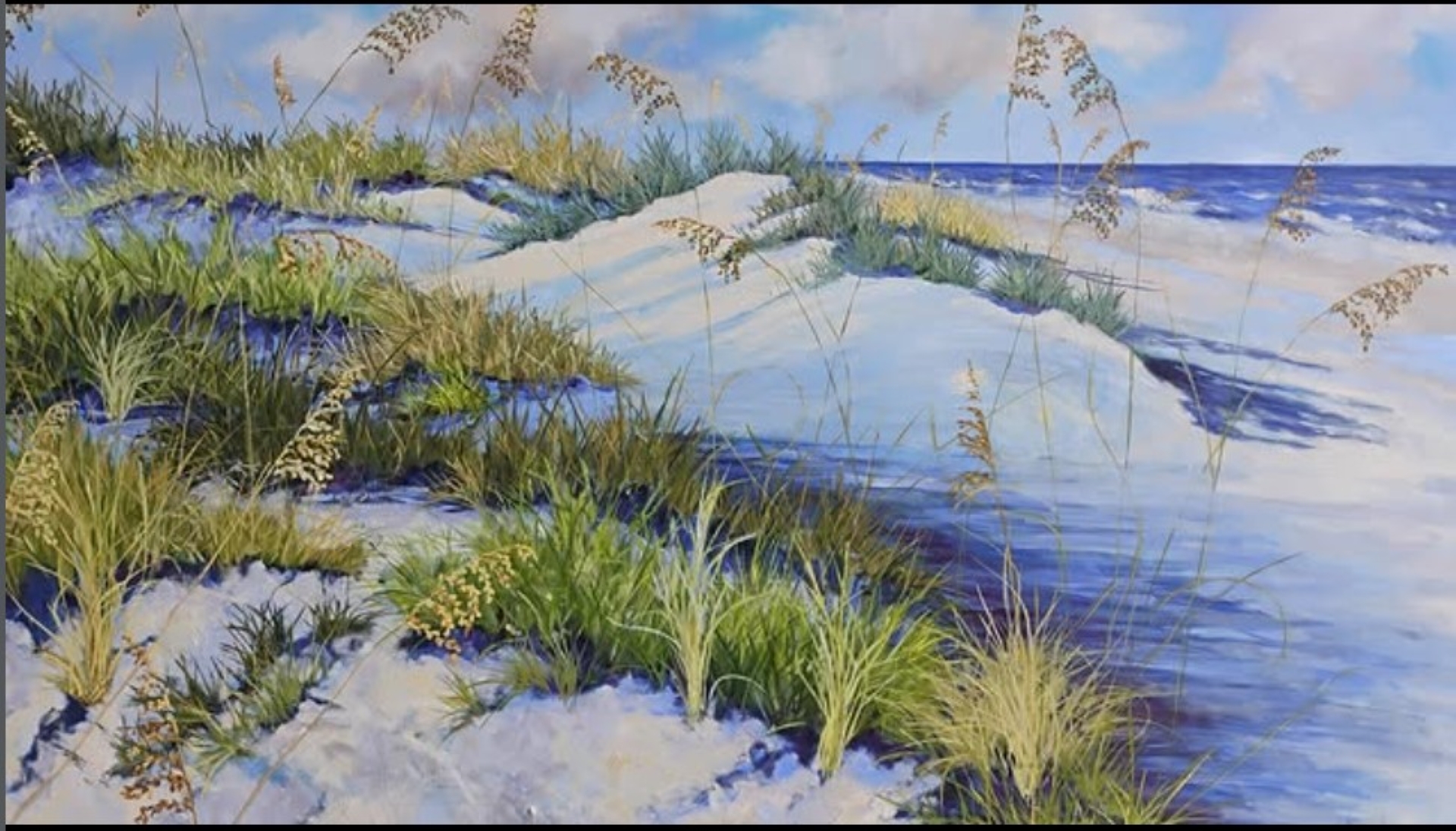 A beach scene with white sand dunes covered in green grass and sea oats, set against a blue sky and ocean in the background.